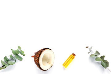 Fresh coconut and oil in a bottle, eucalyptus leaves on white background. Personal hygiene and natural cosmetics concept. Top view, flat lay, copy space