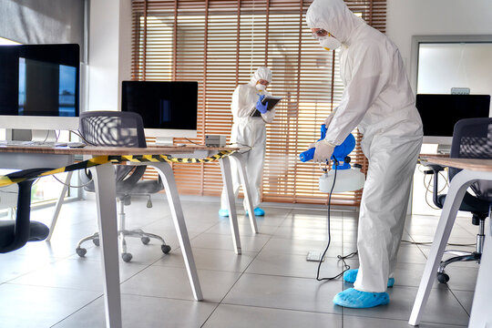Sanitation worker spraying disinfecting chemical at office