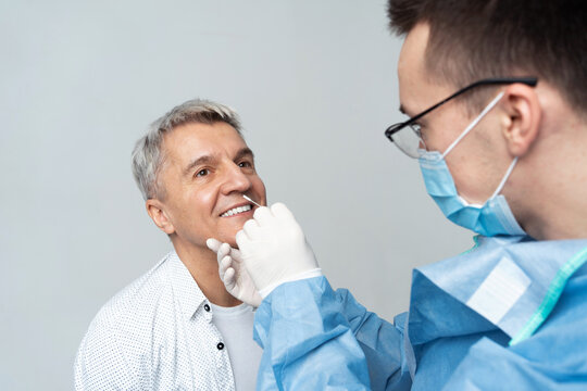 A doctor in a protective coat does a PCR test to a patient in a medical laboratory.