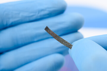 Stripe of gray cellular fiber material in scientist hands. Research for material or coating with...