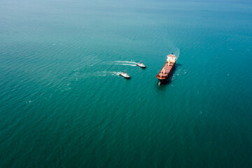red oil ship tank and tugboat sailing on green sea