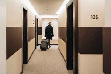 Businessman walking with briefcase and luggage at hotel corridor