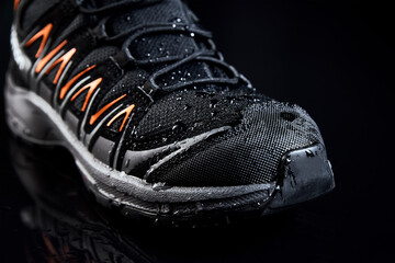 Black male boots for hiking on dark background. Waterproof shoes with water drops, close up