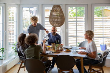 Boy pouring water for brother at dining table