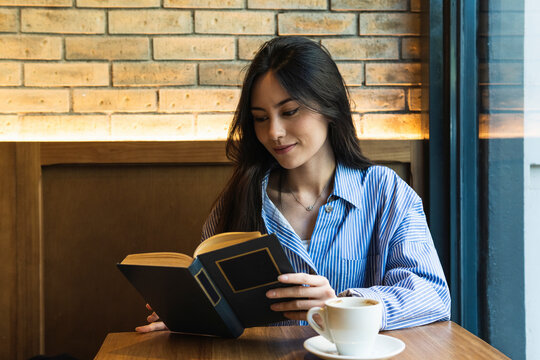 Beautiful Woman Reading Book While Having Coffee At Bar