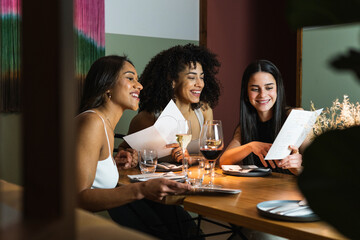 Smiling friends checking menu together in restaurant