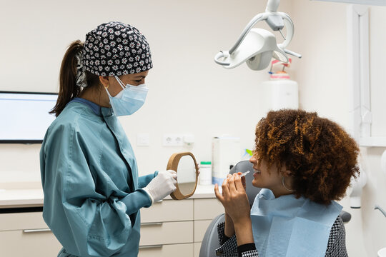 Smiling female patient looking at dentist while wearing dental aligner in clinic