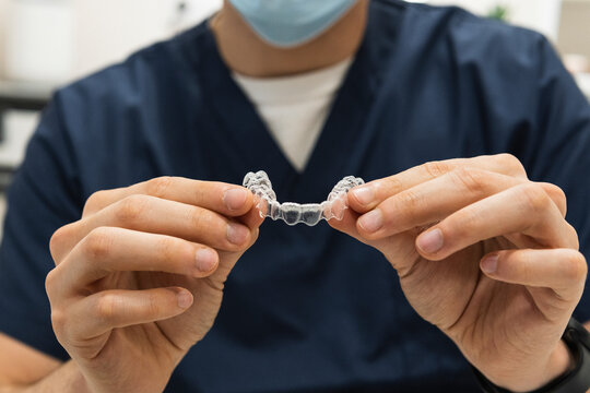 Male dentist holding dental aligner at clinic