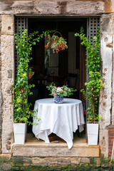 Fototapeta na wymiar Italian restaurant table between flower garlands in window above canal in Venice