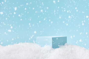 Winter Christmas background with podium for product presentation. Cubic pedestal in a snowdrift, falling snow.