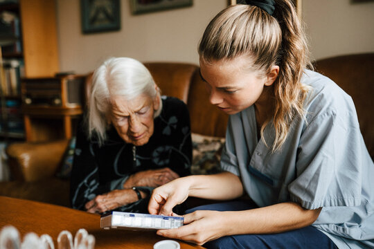 Female nurse explaining medicine dose to senior woman at home