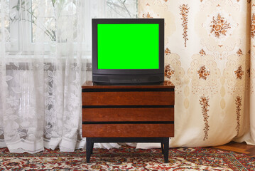 Antique TV with green screen on an antique wooden cabinet, old design in a house in the style of...