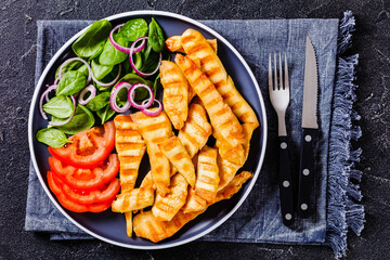 grilled chicken strips on a plate with vegetables