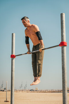 Male sportsperson exercising on high bar during sunny day