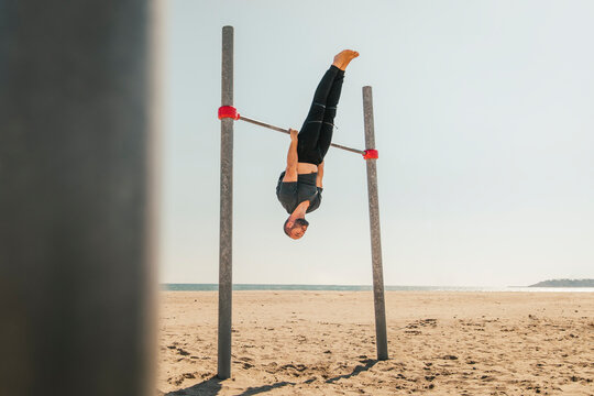 Male athlete practicing on high bar at beach