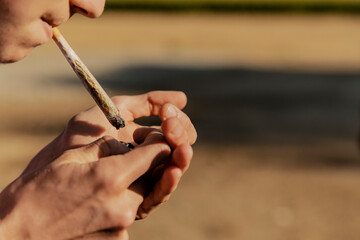 Teenage boy igniting marijuana joint during sunset
