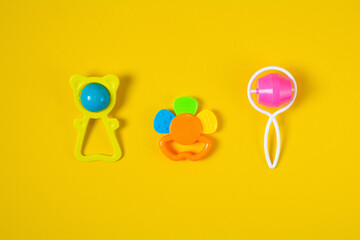 Top view a colorful baby rattle on yellow background. Flat lay newborn rattle toy on colored background. Baby toys concept