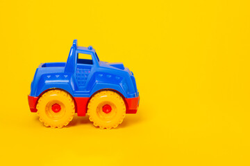 Top view children's toy car on a yellow background with copy space. Flat lay baby toy red-blue car on colored background