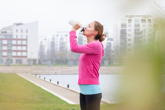 Mature woman drinking water while standing at park