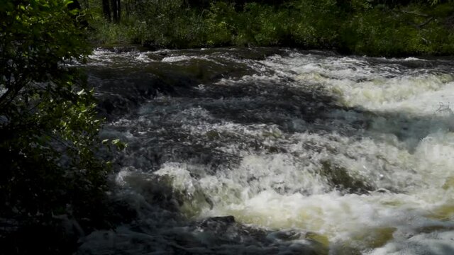 Slow motion river water flowing over the rocks; Ocqueoc Falls, rushing water over rocks in Northwest Michigan after months of rain in late summer--late morning. 456