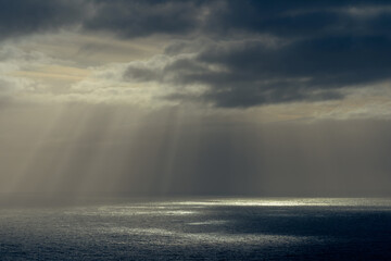 Rays of sun through dark clouds at ocean.