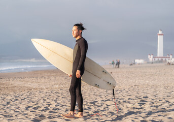 latin surfer walking on the beach with a surfboard getting into the ocean