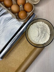 Roll of baking foil, brown parchment paper and paper rolls on a table, top view. Kitchen utensil for cooking.