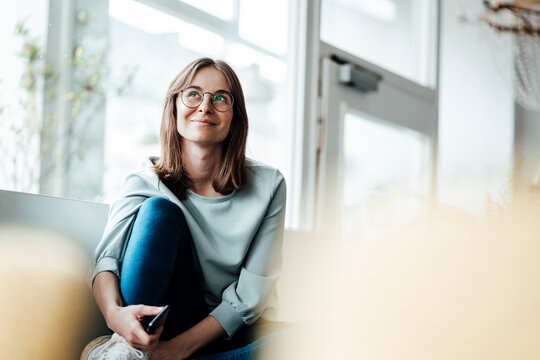 Smiling woman wearing eyeglasses looking away while sitting in cafe