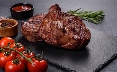 grilled beef steaks with spices on a dark cutting board