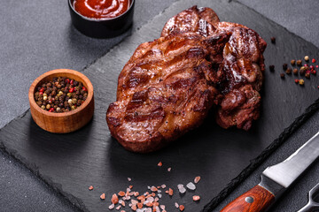 grilled beef steaks with spices on a dark cutting board