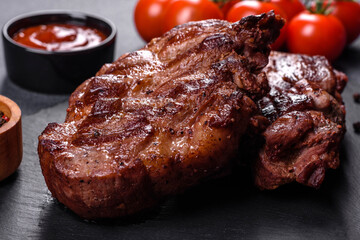 grilled beef steaks with spices on a dark cutting board