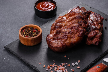 grilled beef steaks with spices on a dark cutting board