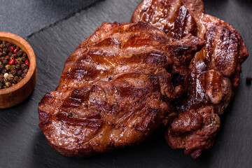 grilled beef steaks with spices on a dark cutting board