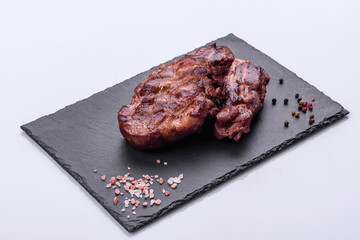 grilled beef steaks with spices on a dark cutting board