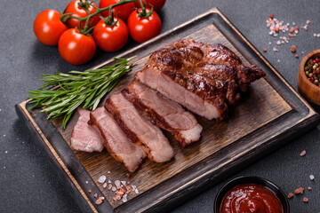 grilled beef steaks with spices on a dark cutting board