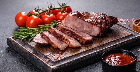 grilled beef steaks with spices on a dark cutting board
