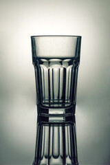 Empty highball glass on a gray background with a beautiful reflection.