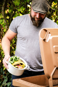 Mature man throwing kitchen scraps into bio-waste container