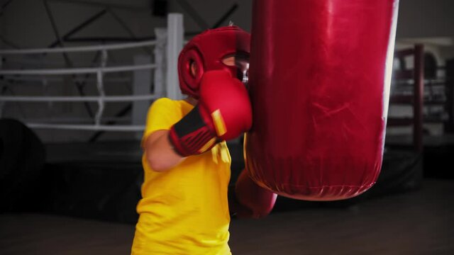 Little boy boxer punching a big punching bag on training