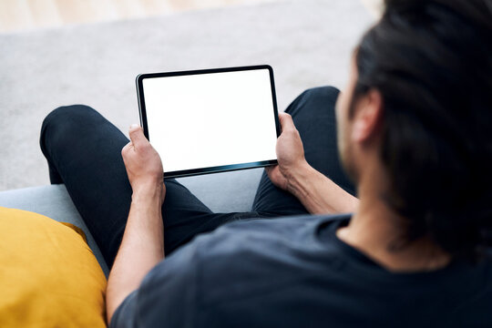 Young man holding digital tablet while sitting on sofa