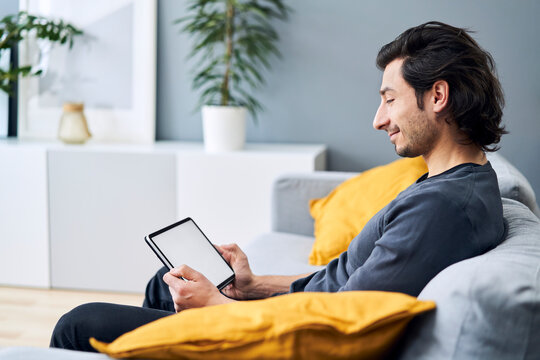 Man using digital tablet while sitting on sofa
