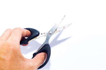 small black scissors in hand on an isolated white background. want to cut something 