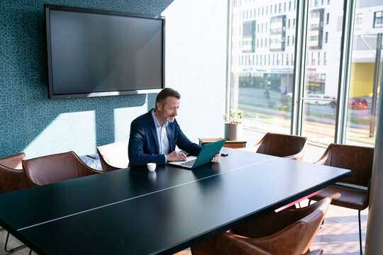 Male entrepreneur using laptop at conference table in office