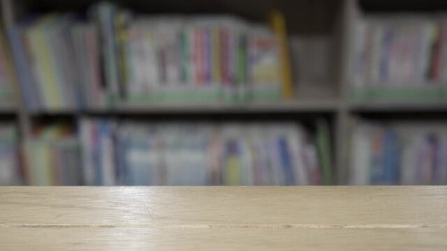 Close up on The wooden table in the library. The blurred background is bookshelves and books.