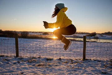 Woman jumping while doing exercise during winter