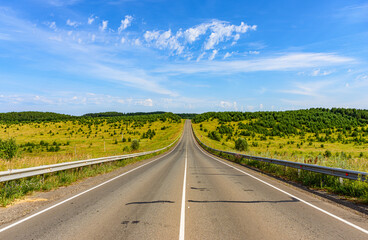 The road of regional significance rises to a hill covered with small groups of trees