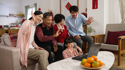 smiling asian big family waving hi and wishing friends a happy chinese new year with congratulation...