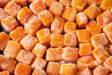 Frozen fresh carrot cube pieces closeup background