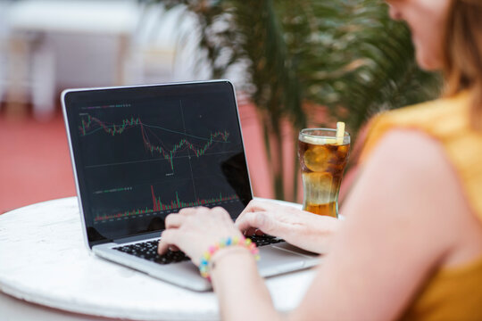 Woman trading on stock market through laptop at bar
