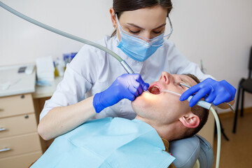 A female dentist treats tooth decay on a male patient's teeth at a dental clinic during the...